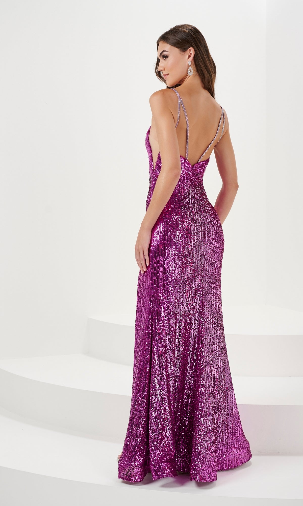A woman stands on a white background, wearing the Illusion-Sides Long Sequin Prom Dress 14171—a floor-length, sleeveless purple gown with a low back and double shoulder straps.
